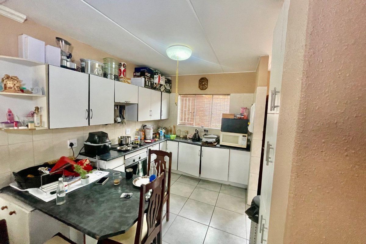 A functional kitchen featuring built-in cabinetry, laminate countertops, and tiled flooring, offering a practical layout with potential for modern cosmetic updates.