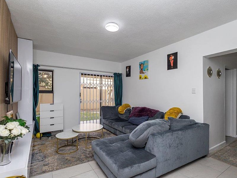A living room featuring tiled flooring, a sliding glass door with a security gate, and access to an outdoor area.
