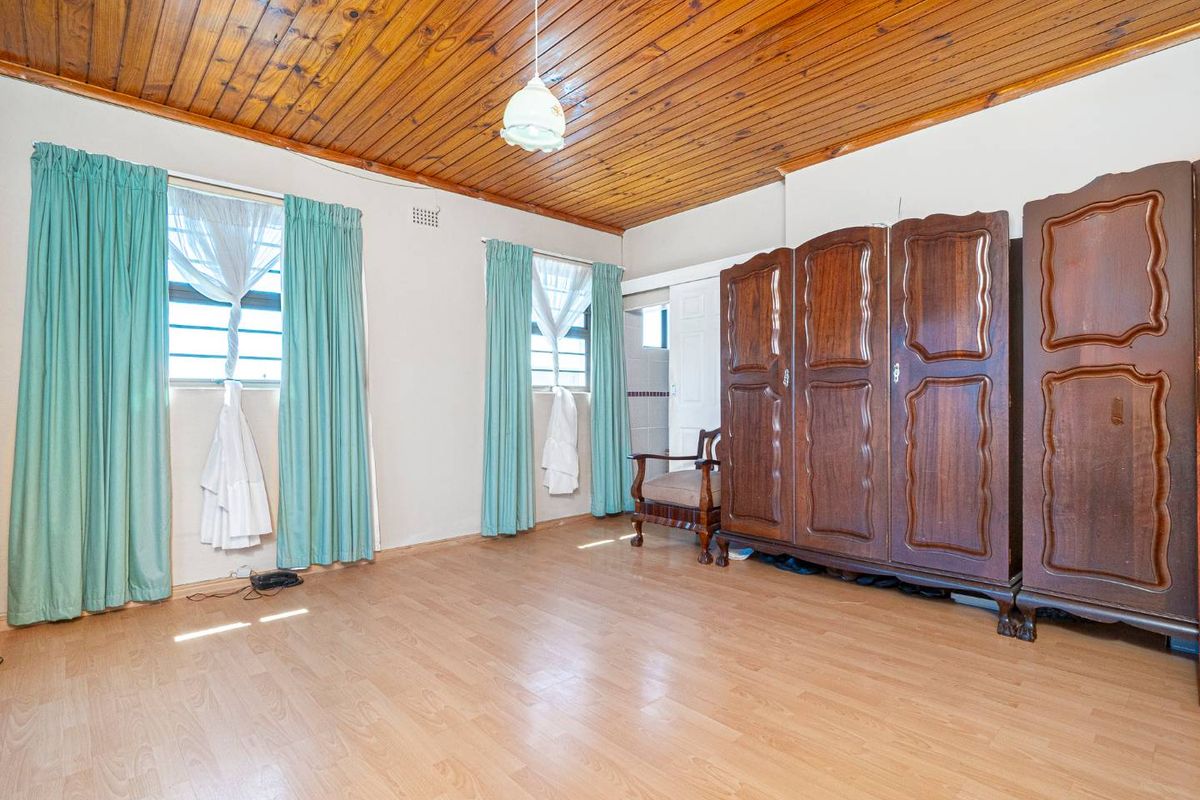 Spacious bedroom featuring laminate flooring and a distinctive timber tongue and groove ceiling, offering a functional layout with natural light.