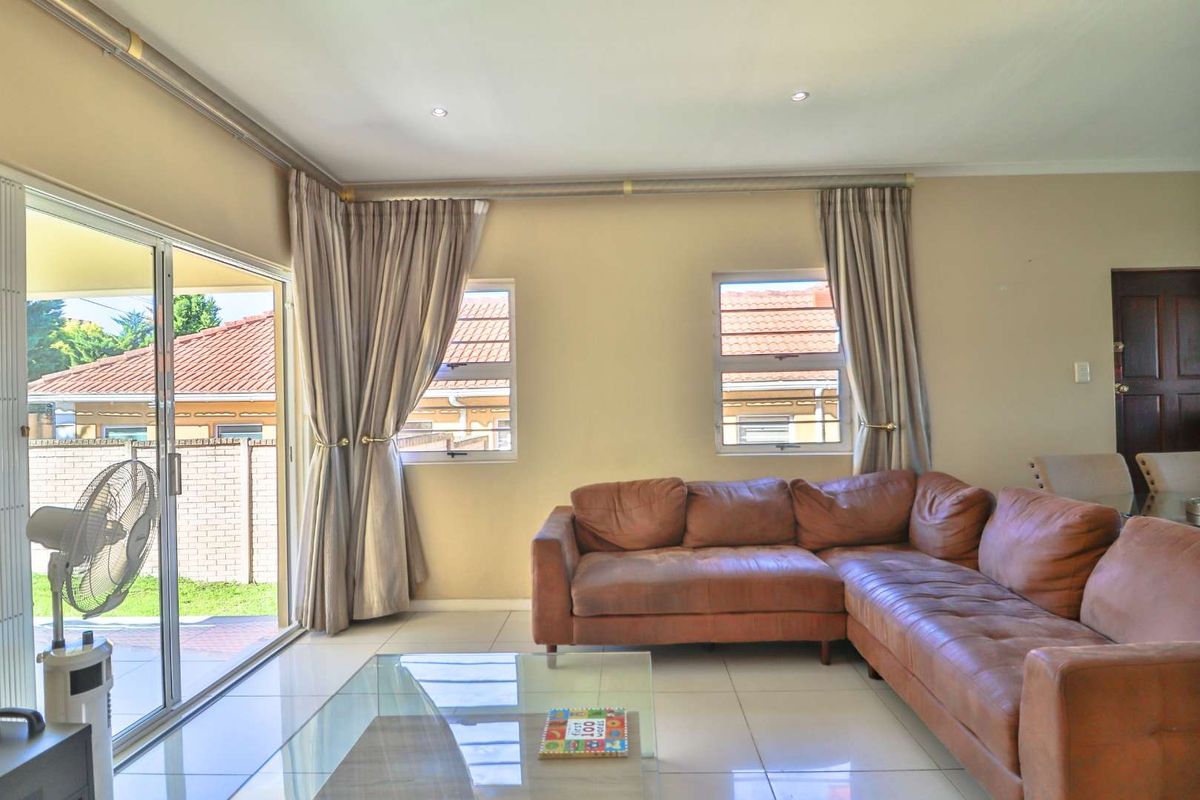 A bright living room featuring large sliding glass doors that open to an outdoor patio area, complemented by tiled flooring and neutral wall finishes.