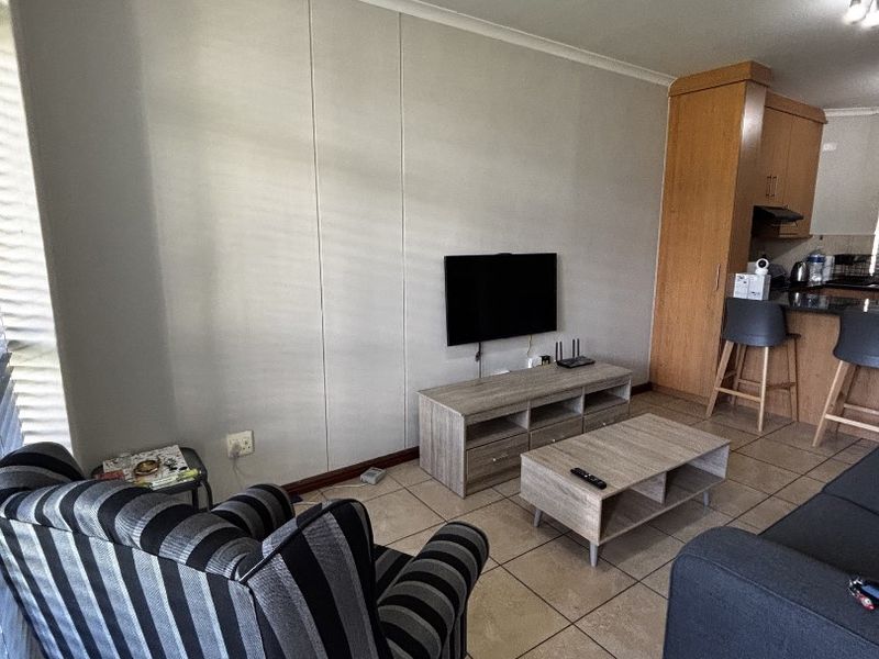 Open plan living area featuring tiled flooring and a connected kitchen with breakfast bar and built-in cabinetry.