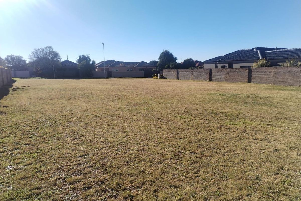 A vacant residential plot of land featuring level ground, enclosed by perimeter brick boundary walls in a developed suburban neighborhood.