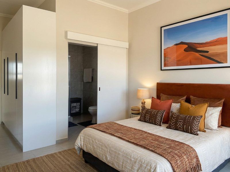 A well-maintained bedroom featuring a built-in wardrobe, tiled flooring, and direct access to an en-suite bathroom through a sliding door.