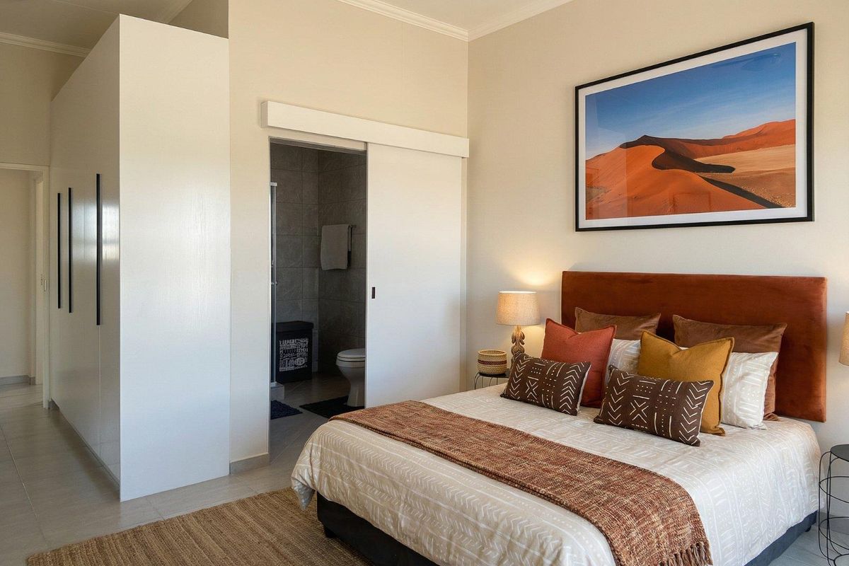 A well-maintained bedroom featuring a built-in wardrobe, tiled flooring, and direct access to an en-suite bathroom through a sliding door.