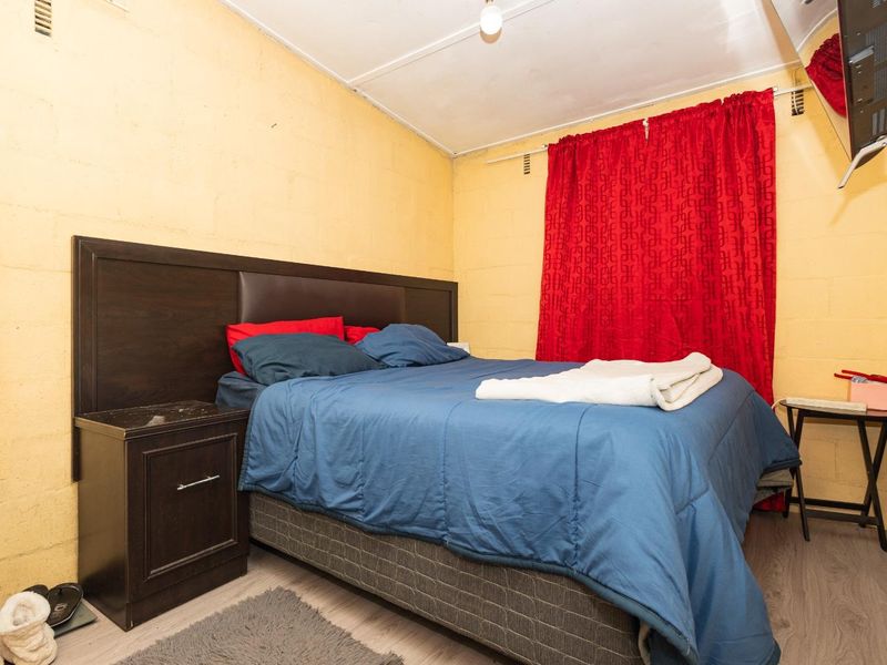 A bedroom featuring laminate flooring and exposed blockwork walls, offering a functional space with potential for cosmetic updates.