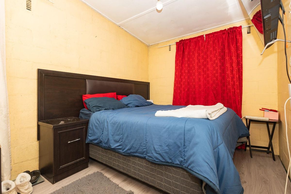 A bedroom featuring laminate flooring and exposed blockwork walls, offering a functional space with potential for cosmetic updates.