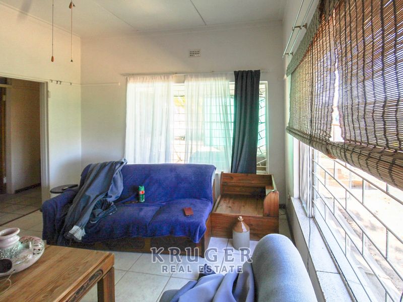 A living room featuring tiled flooring and large windows fitted with security bars, offering a functional and well-lit space.