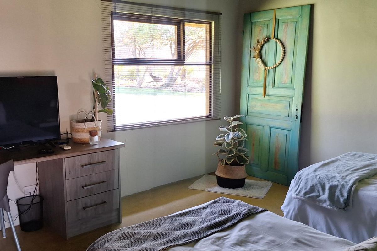A bedroom featuring a window with blinds, a decorative door, and neutral wall finishes, providing a functional and comfortable living space.