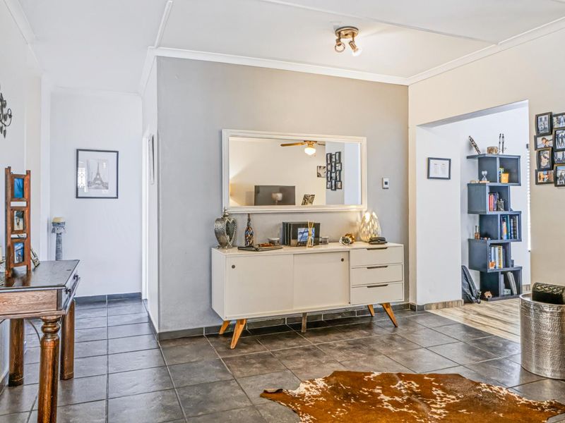 A living area featuring dark tiled flooring, neutral wall tones, and a coved ceiling with a central light fixture.