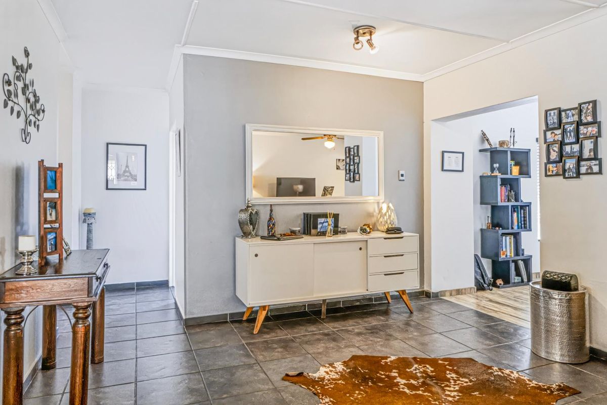 A living area featuring dark tiled flooring, neutral wall tones, and a coved ceiling with a central light fixture.