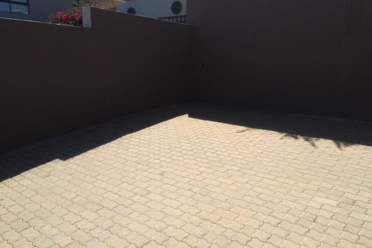 A paved outdoor courtyard area enclosed by high boundary walls, providing a private and low-maintenance exterior space.