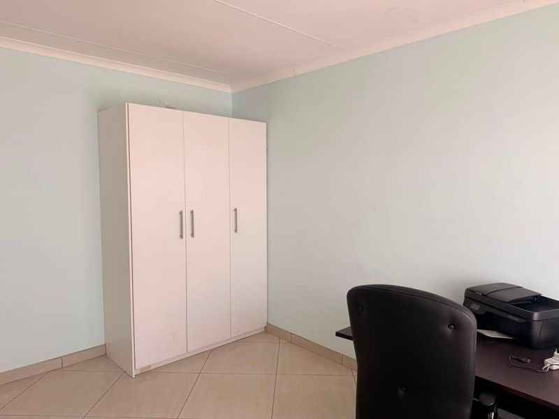 A bedroom featuring tiled flooring, coved ceilings, and a built-in wardrobe, providing a functional and neutral living space.