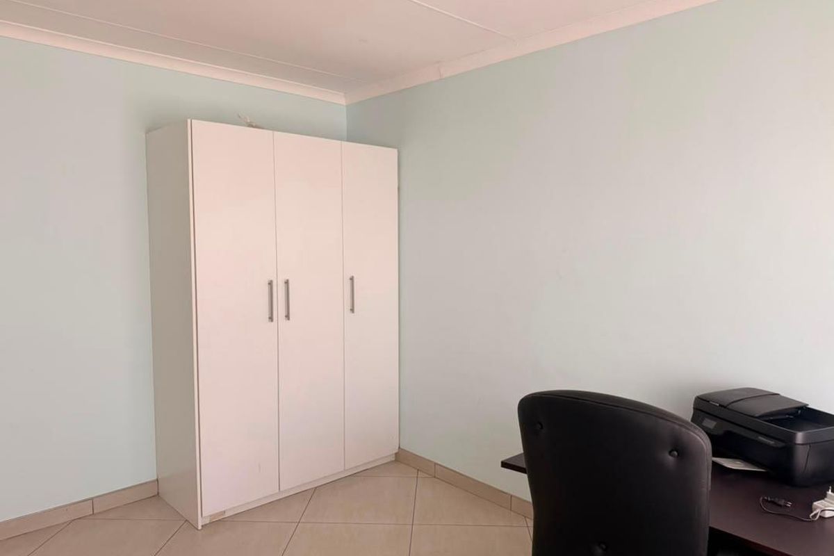 A bedroom featuring tiled flooring, coved ceilings, and a built-in wardrobe, providing a functional and neutral living space.
