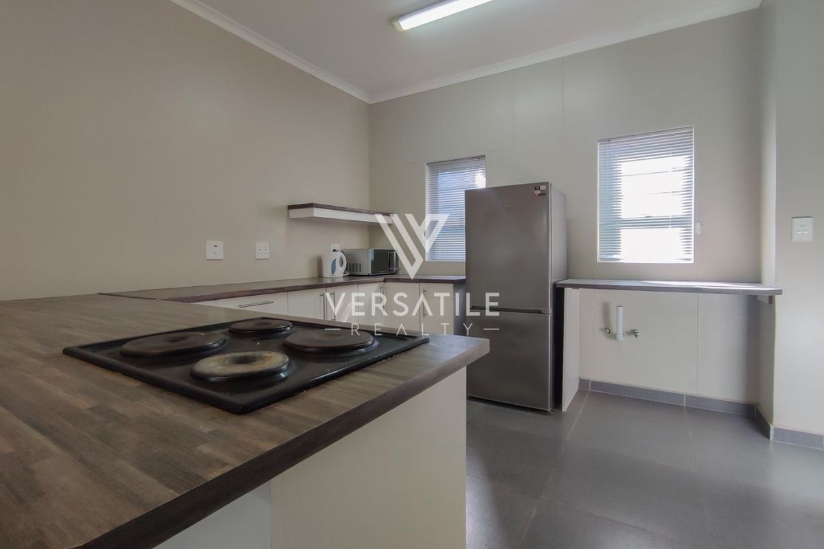 Functional kitchen featuring laminate countertops, a built-in electric hob, and dedicated plumbing connections for appliances.