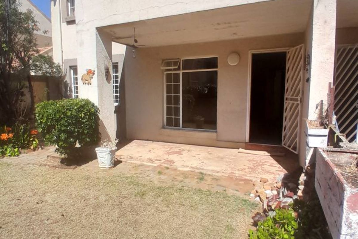 Rear view of the apartment featuring a covered patio area, paved flooring, and a small private garden space.