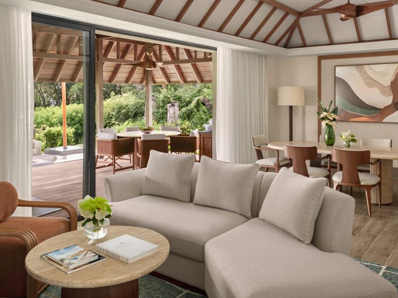 Spacious open-plan living and dining area featuring vaulted timber ceilings, seamless indoor-outdoor flow through sliding glass doors, and access to a private timber deck.