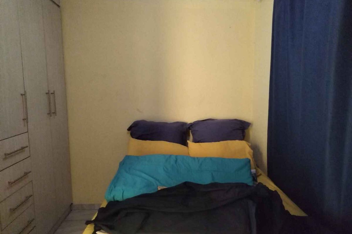 A compact bedroom featuring built-in cabinetry and tiled flooring, providing functional storage space.