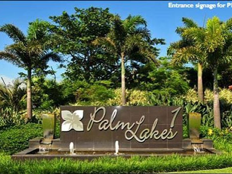 Entrance signage and water feature for the Palm Lakes estate, surrounded by mature palm trees and manicured landscaping.