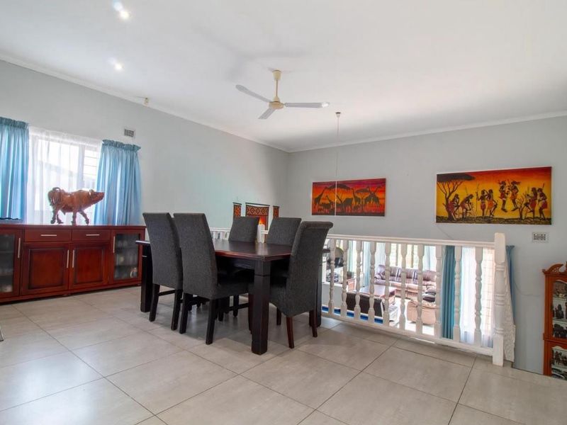 Spacious dining area featuring tiled flooring, a ceiling fan, and a decorative balustrade overlooking the lower level living space.