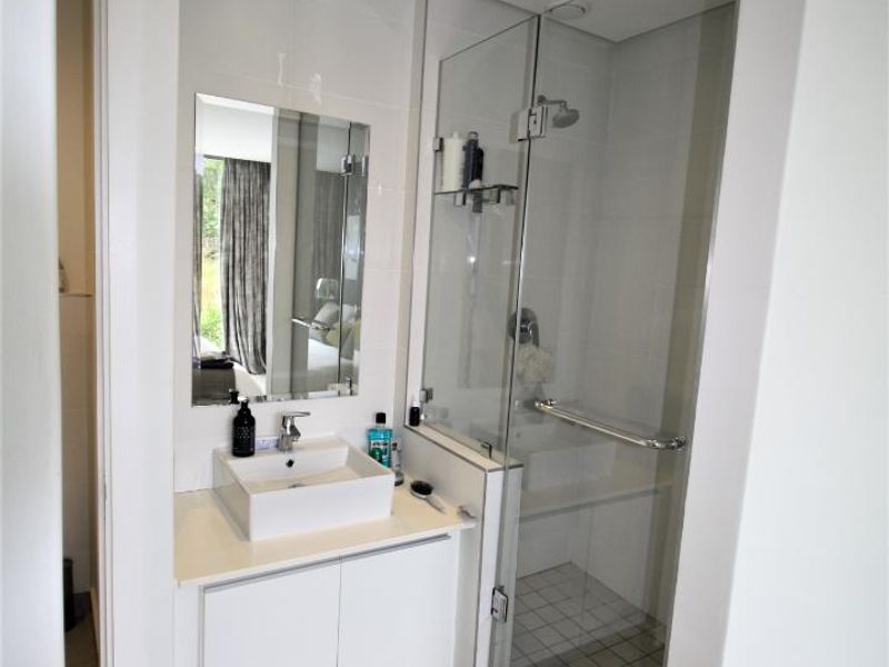 Modern bathroom featuring a vessel sink with vanity storage, a glass-enclosed shower, and neutral tiled finishes.