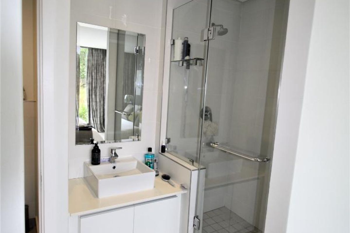 Modern bathroom featuring a vessel sink with vanity storage, a glass-enclosed shower, and neutral tiled finishes.
