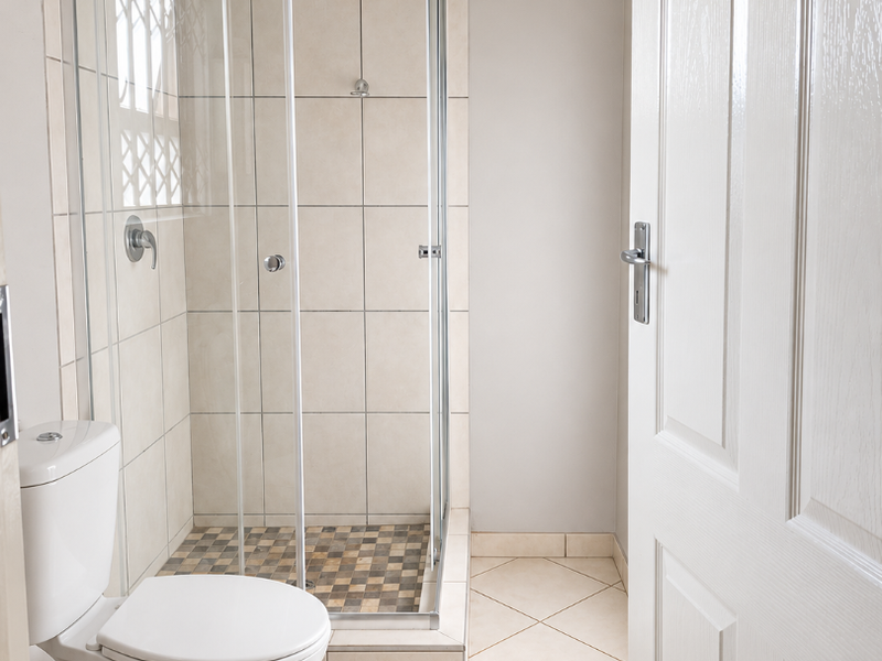 A clean and functional bathroom featuring a glass-enclosed shower, tiled walls, and neutral floor tiles.