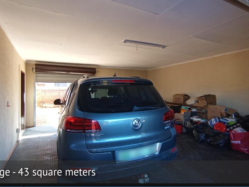 Spacious 43 square meter garage featuring a functional layout, overhead lighting, and a side window, providing ample storage and vehicle parking space.
