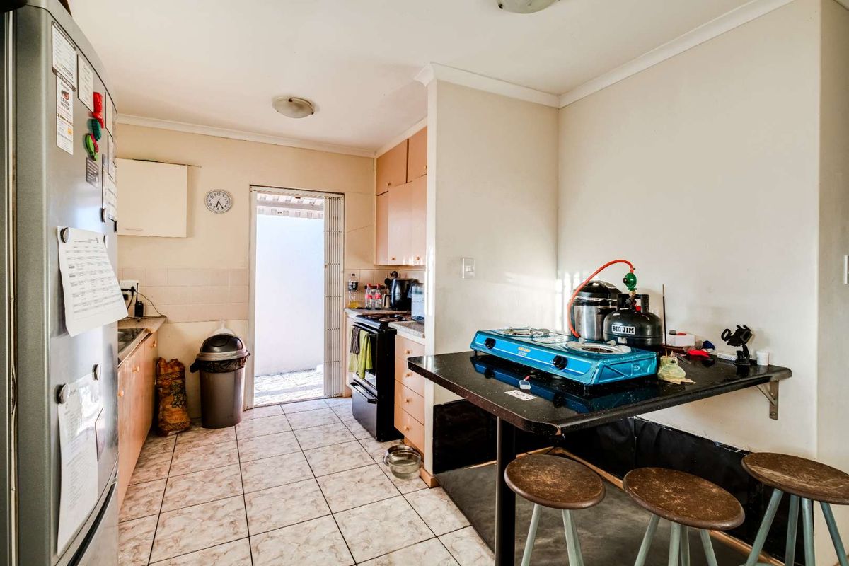 A compact kitchen featuring tiled flooring, built-in cabinetry, and a breakfast bar area with direct access to an outdoor space.