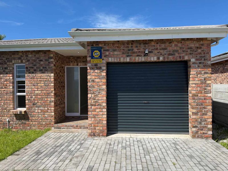 Front elevation of a face brick house featuring a single garage with a roll-up door and a paved driveway.