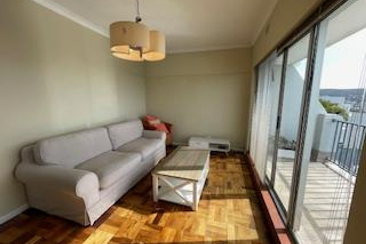 A living room featuring parquet flooring, cove cornicing, and large sliding glass doors that provide access to an outdoor balcony area.