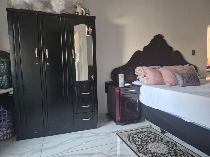 A bedroom featuring white marble-look tiled flooring and neutral wall finishes.