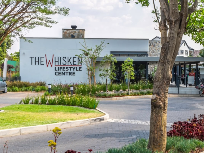 Exterior view of The Whisken Lifestyle Centre, featuring a well-maintained paved driveway, landscaped gardens, and modern architectural stone cladding.