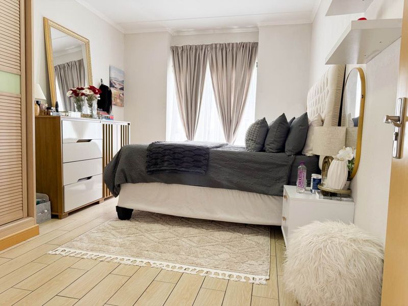 A well-maintained bedroom featuring light-toned tiled flooring, a built-in wardrobe, and coved ceiling details, offering a clean and functional living space.