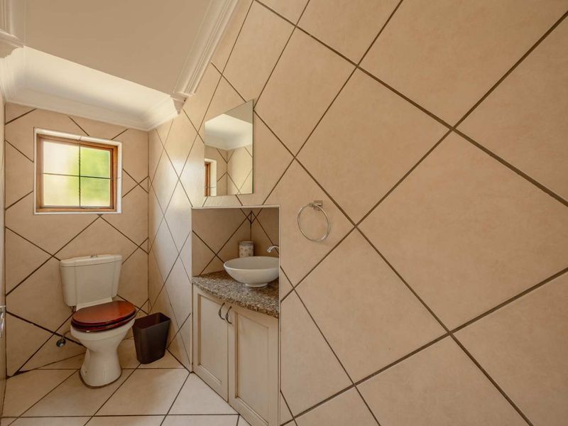 A compact guest bathroom featuring diagonal wall tiling, a vanity with a granite countertop, vessel sink, and a standard toilet.