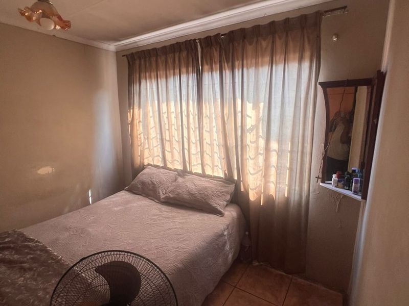 A compact bedroom featuring tiled flooring and a ceiling light fixture, requiring some cosmetic updates to the wall finishes.
