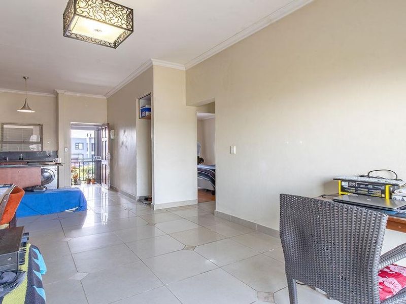 Open-plan living area featuring tiled flooring, integrated kitchen cabinetry, and direct access to an outdoor balcony space.