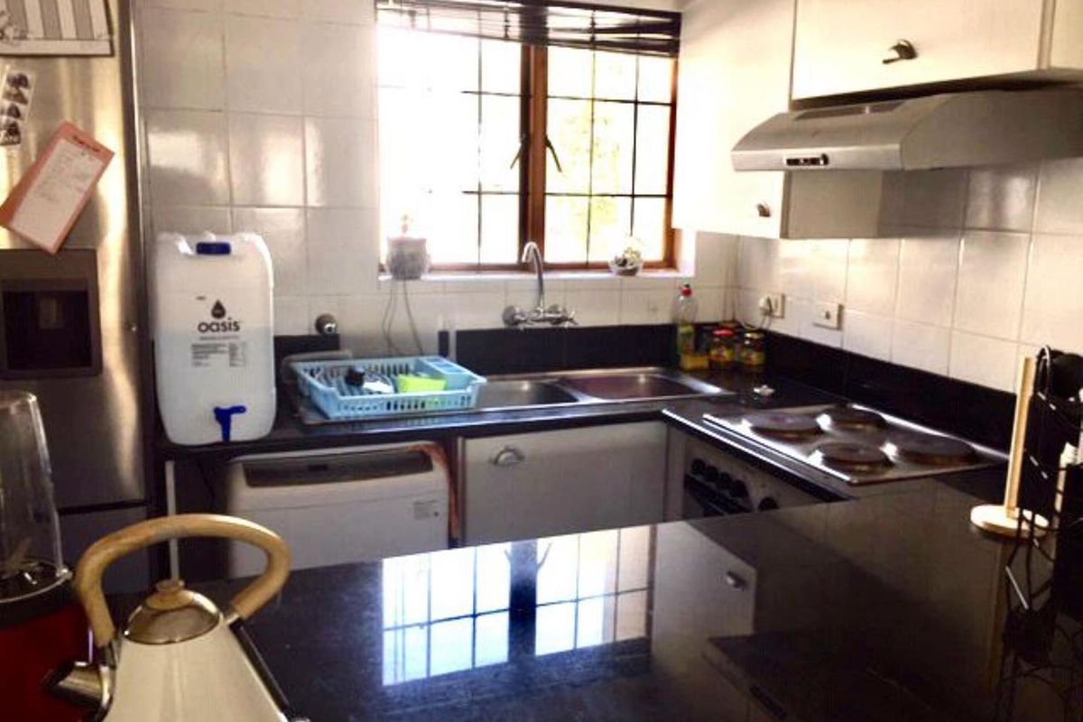 A functional kitchen featuring dark granite countertops, built-in cabinetry, a double sink, and an integrated electric hob with an extractor fan.
