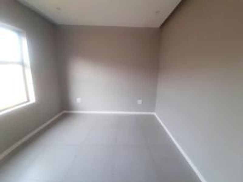 A clean, empty bedroom featuring neutral wall paint, tiled flooring, and recessed downlighting, providing a blank canvas for personalization.