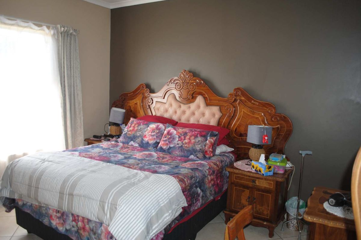 A bedroom featuring a dark accent wall, tiled flooring, and a window with curtains.