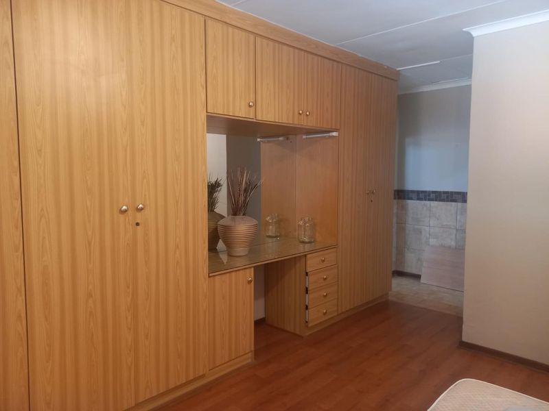 Bedroom featuring extensive built-in wooden cabinetry with an integrated vanity area and durable laminate flooring.