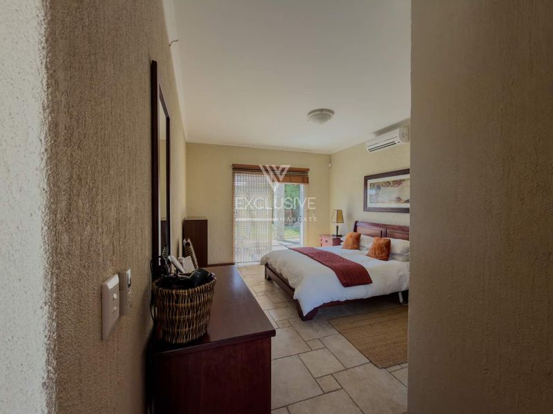 A bedroom featuring tiled flooring, a split-system air conditioner, and a sliding glass door providing access to the exterior.