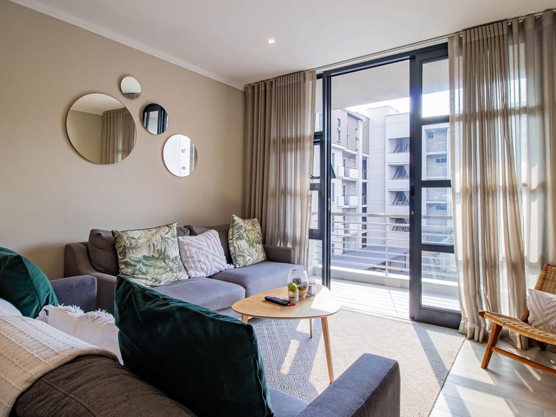 A bright and modern living room featuring large glass sliding doors that open onto a private balcony, providing ample natural light.
