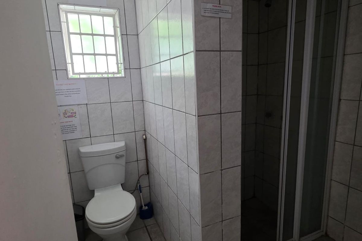 A functional bathroom featuring a tiled shower enclosure, a standard toilet, and a small window for ventilation.