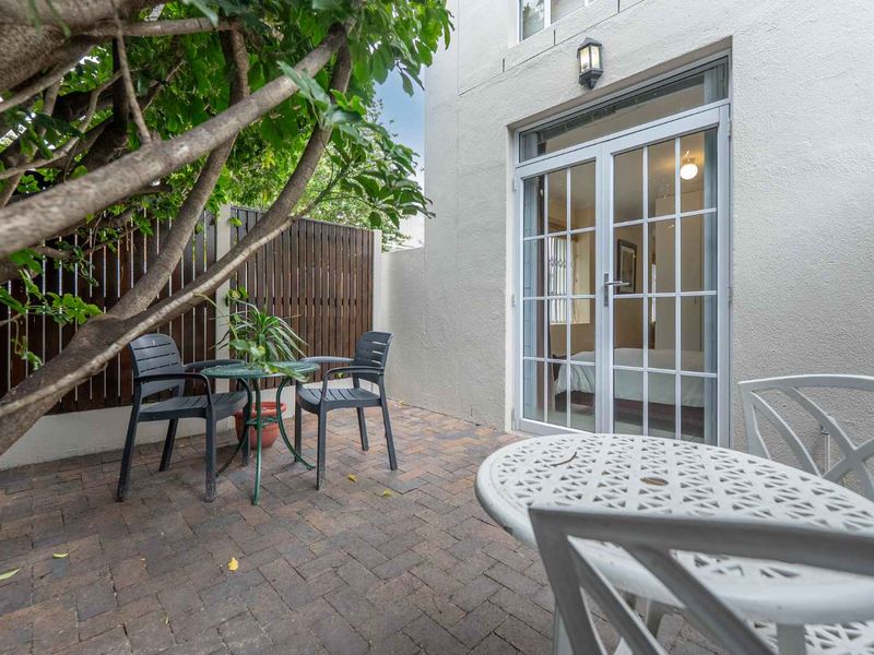 A private paved patio area featuring timber slat fencing and direct access to the interior through white-framed french doors.