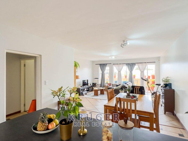 Spacious open-plan living and dining area featuring tiled flooring, modern recessed lighting, and large sliding glass doors leading to an outdoor balcony.