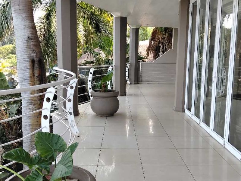 A spacious covered balcony featuring tiled flooring, modern metal balustrades, and large glass sliding doors providing seamless indoor-outdoor flow.