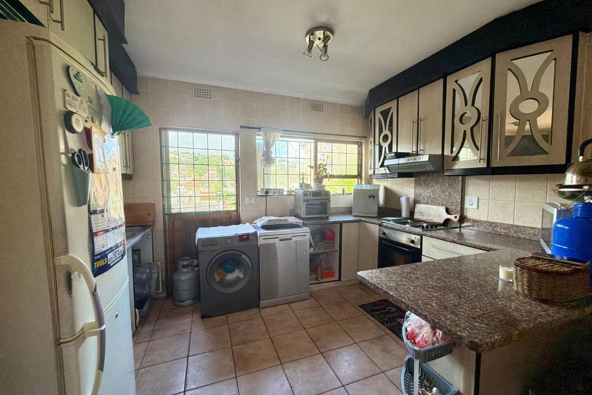 Functional kitchen featuring tiled flooring, built-in cabinetry, laminate countertops, and integrated cooking appliances, with direct access to an exterior security door.