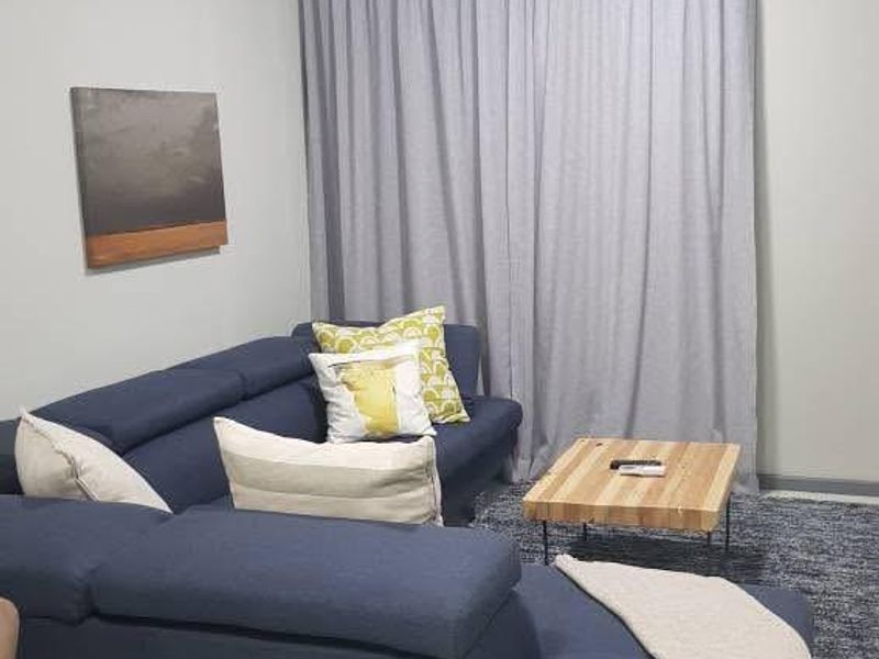 A comfortable living room featuring neutral tiled flooring and full-length curtains, providing a clean and functional space for relaxation.