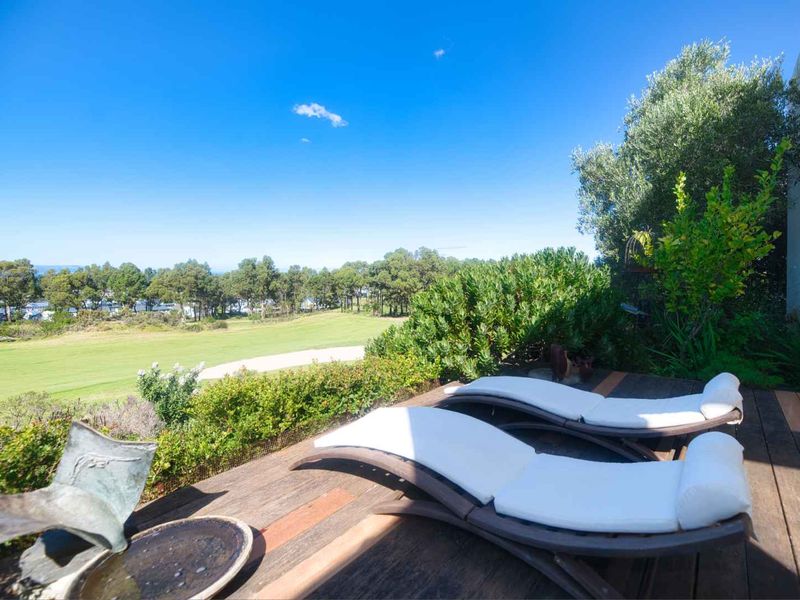A spacious timber deck patio overlooking a lush green golf course and surrounding landscape, providing a serene outdoor entertainment area.