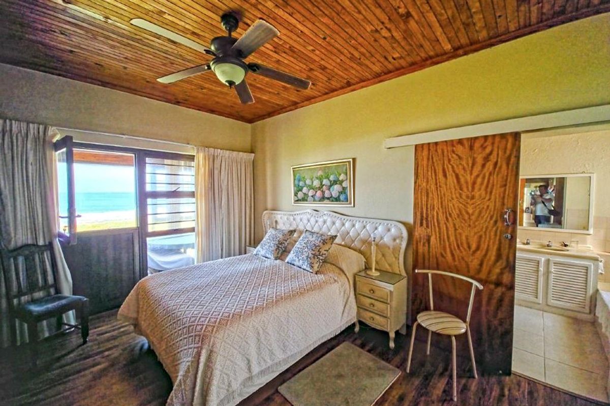 Bedroom featuring a timber-clad ceiling, ceiling fan, and direct access to a balcony with ocean views, plus an en-suite bathroom.